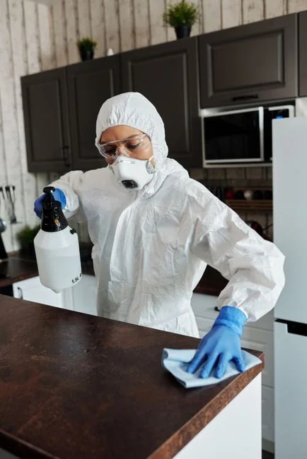 A professional cleaner in red coveralls vacuuming a modern living room with a yellow vacuum cleaner.